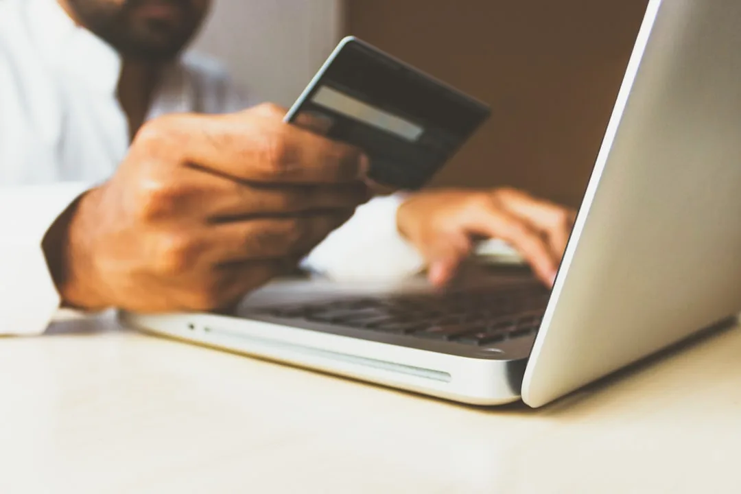 Hands holding a payment card near a keyboard